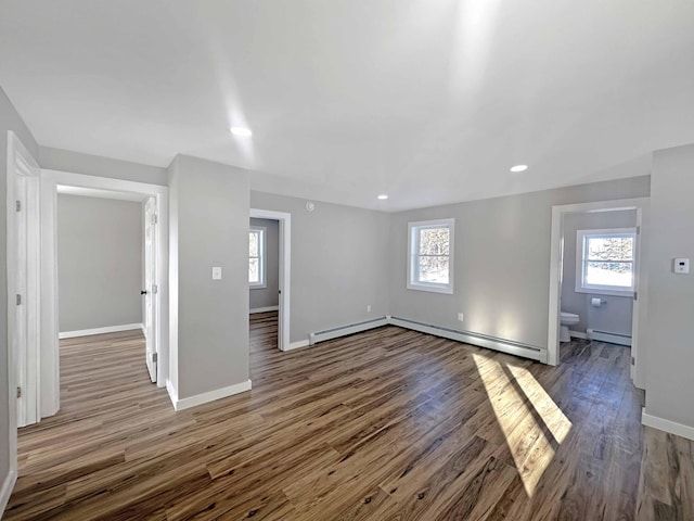 unfurnished living room featuring a baseboard radiator, plenty of natural light, and dark hardwood / wood-style floors