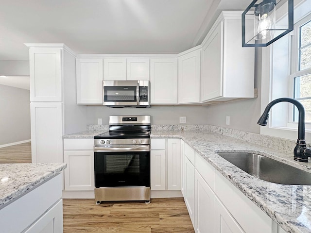 kitchen with light wood-type flooring, appliances with stainless steel finishes, sink, and white cabinets