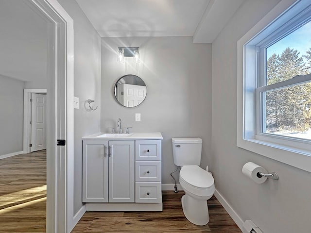 bathroom featuring baseboard heating, wood-type flooring, toilet, and vanity