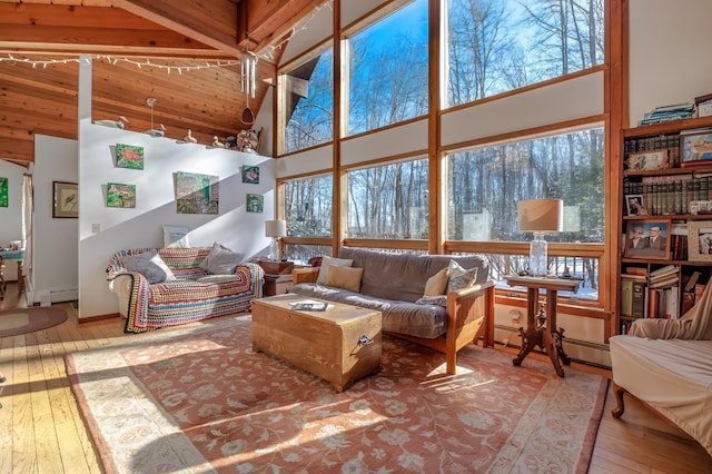 living room with a towering ceiling, light hardwood / wood-style flooring, and a baseboard heating unit