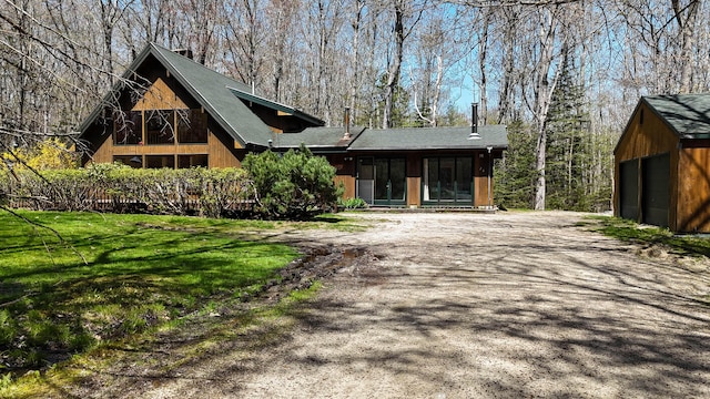 view of front of property featuring an outdoor structure, a front lawn, a chimney, and a detached garage