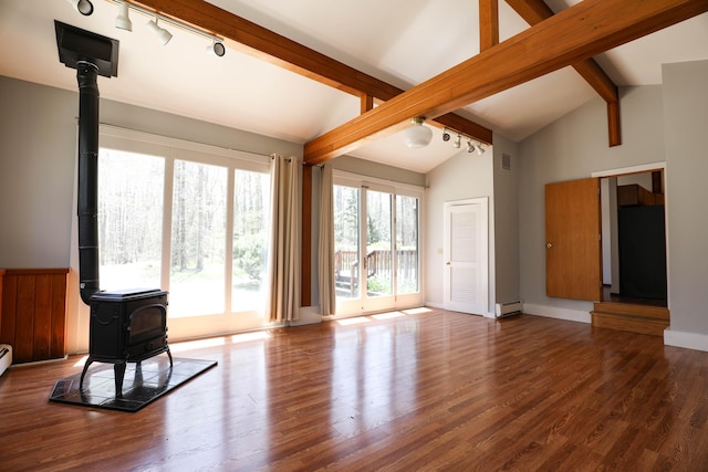 unfurnished living room featuring a wood stove, rail lighting, baseboard heating, and wood finished floors