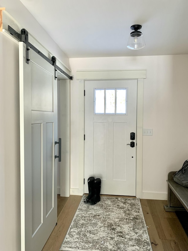 foyer entrance with a barn door and light hardwood / wood-style flooring