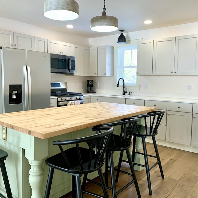 kitchen with butcher block counters, sink, a breakfast bar area, and a center island