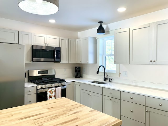 kitchen with sink, wooden counters, gray cabinets, pendant lighting, and stainless steel appliances