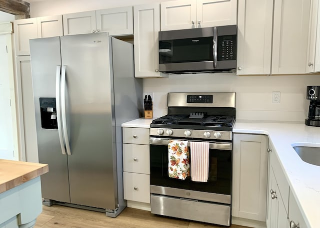 kitchen featuring stainless steel appliances, light hardwood / wood-style floors, and white cabinets