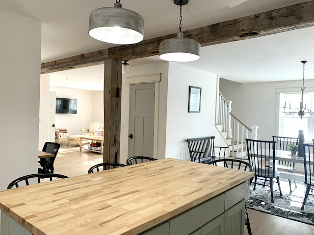 dining room with a notable chandelier, beamed ceiling, and light wood-type flooring