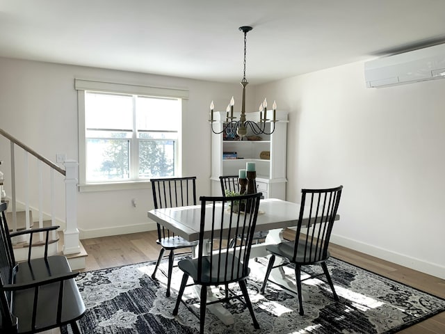 dining room featuring hardwood / wood-style flooring, a wall mounted AC, and a chandelier