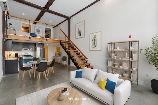 living room featuring a high ceiling, sink, a wall mounted air conditioner, and concrete floors