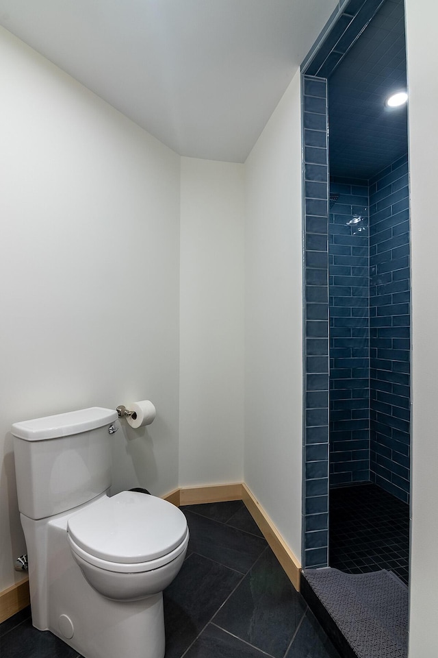 bathroom with tile patterned flooring, tiled shower, and toilet