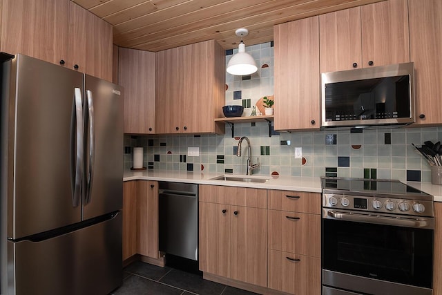 kitchen featuring sink, decorative backsplash, hanging light fixtures, dark tile patterned floors, and stainless steel appliances