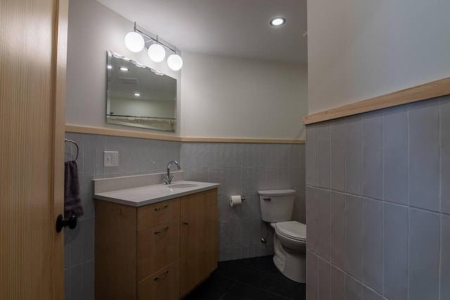 bathroom with vanity, tile patterned floors, tile walls, and toilet