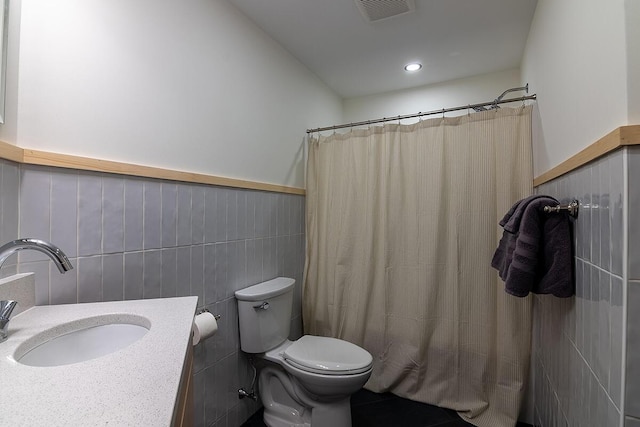 bathroom with a shower with curtain, vanity, toilet, and tile walls