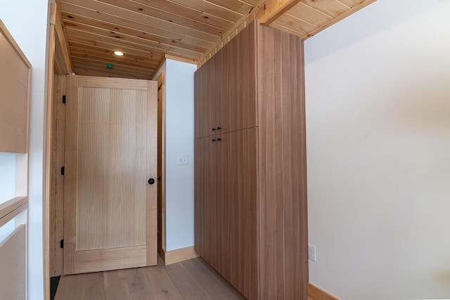 corridor featuring light hardwood / wood-style floors and wooden ceiling