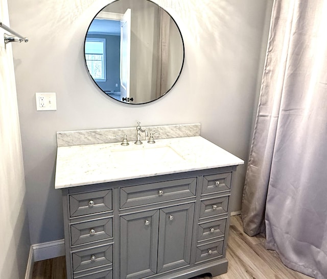 full bath with wood finished floors, vanity, and baseboards