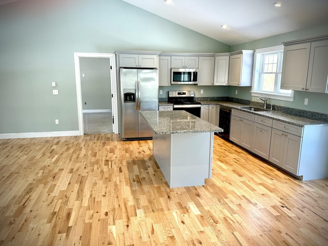 kitchen featuring stone counters, a sink, appliances with stainless steel finishes, gray cabinets, and a center island