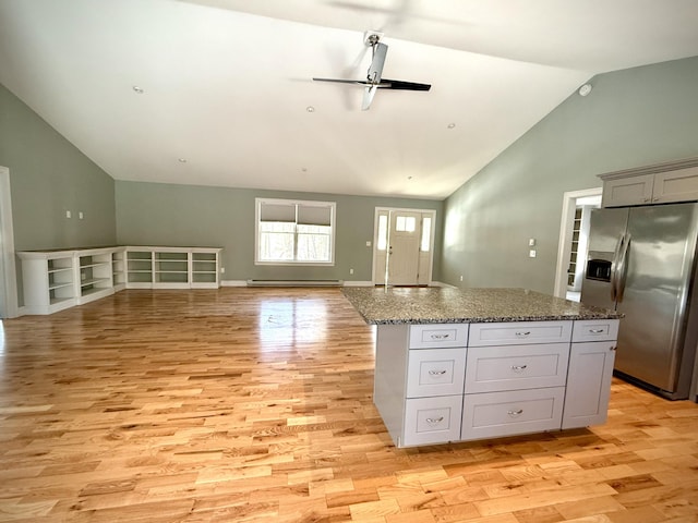 kitchen featuring stainless steel refrigerator with ice dispenser, open floor plan, vaulted ceiling, a kitchen island, and light wood-type flooring