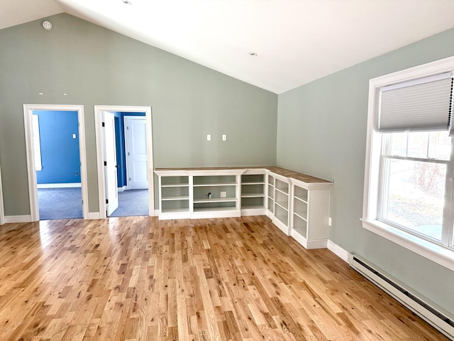 empty room featuring a baseboard heating unit, high vaulted ceiling, light wood finished floors, and baseboards