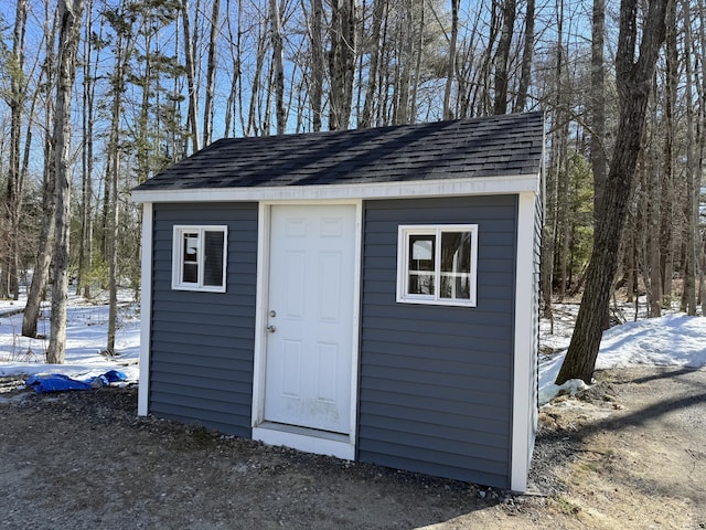 snow covered structure with an outbuilding and a shed