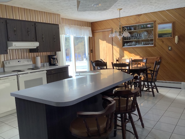 kitchen with pendant lighting, white appliances, a kitchen breakfast bar, a textured ceiling, and light tile patterned flooring