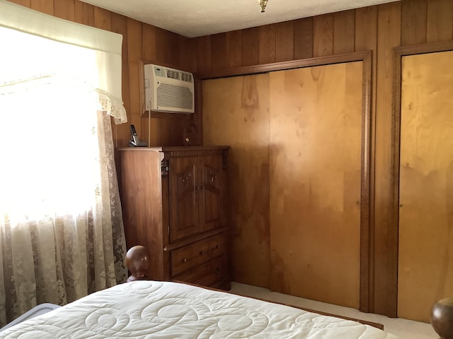 bedroom featuring wooden walls, a wall unit AC, and a closet