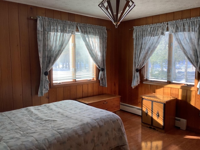 bedroom featuring multiple windows, hardwood / wood-style flooring, and baseboard heating