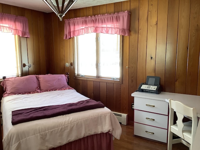 bedroom with hardwood / wood-style flooring, wooden walls, and baseboard heating