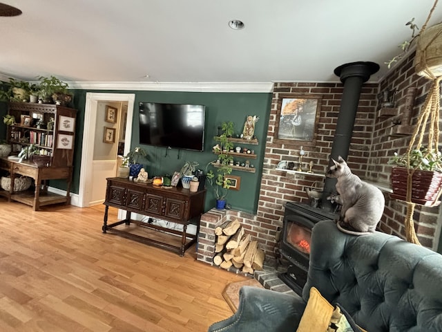 living room with crown molding, brick wall, a wood stove, and light hardwood / wood-style flooring