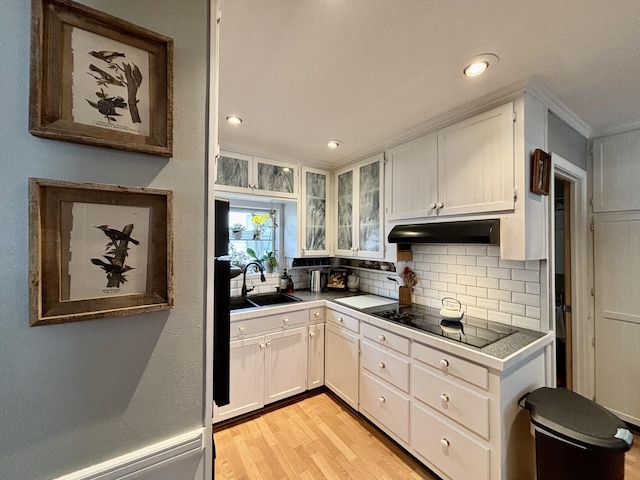 kitchen featuring sink, tasteful backsplash, light wood-type flooring, black electric stovetop, and white cabinets