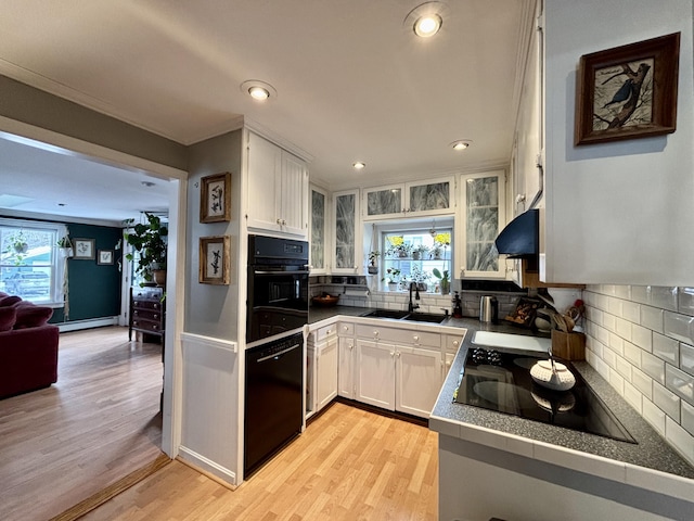 kitchen featuring white cabinets, a baseboard heating unit, sink, and black appliances