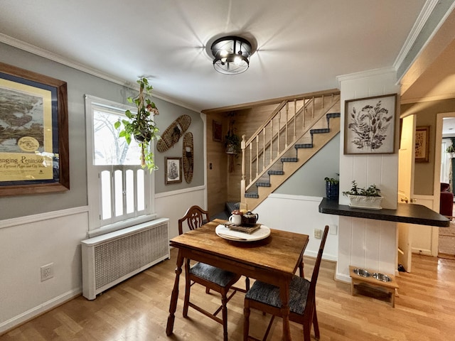 dining space with crown molding, radiator, and hardwood / wood-style floors