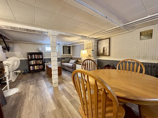 dining space with a drop ceiling, hardwood / wood-style flooring, and ornate columns