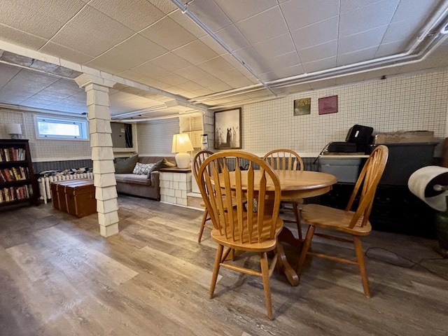 dining area featuring wood-type flooring and decorative columns