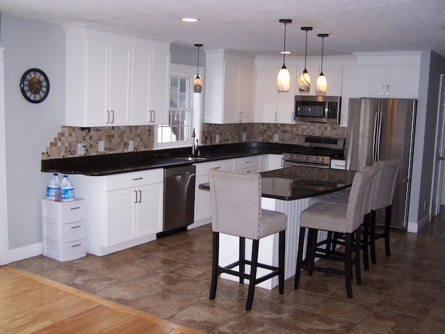 kitchen featuring white cabinetry, appliances with stainless steel finishes, a breakfast bar, and pendant lighting