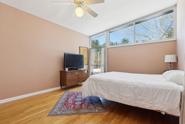 bedroom featuring hardwood / wood-style floors, ceiling fan, and a wall of windows