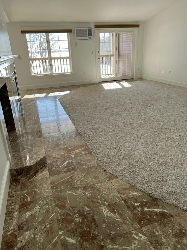 unfurnished living room with dark carpet, a wall mounted AC, and a high end fireplace