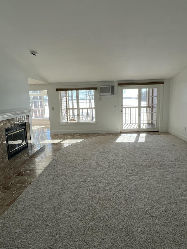 unfurnished living room with dark colored carpet, an AC wall unit, and a fireplace