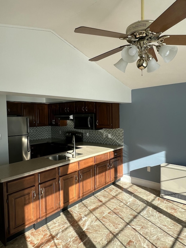 kitchen featuring vaulted ceiling, sink, backsplash, and stainless steel refrigerator