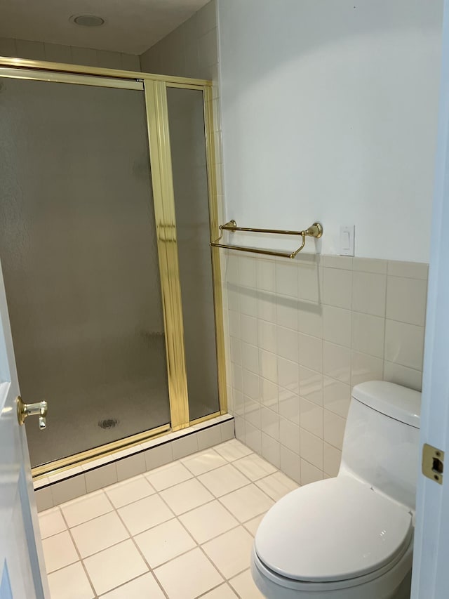 bathroom with tile walls, a shower with shower door, tile patterned floors, and toilet