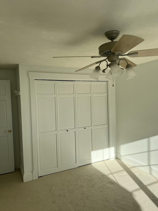 unfurnished bedroom with light carpet, ceiling fan, and a closet