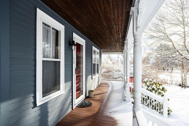 snow covered back of property featuring covered porch