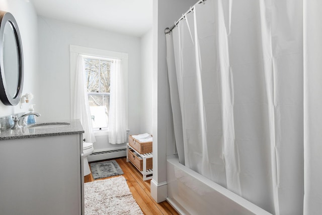 full bathroom with hardwood / wood-style floors, shower / bath combination with curtain, vanity, a baseboard heating unit, and toilet