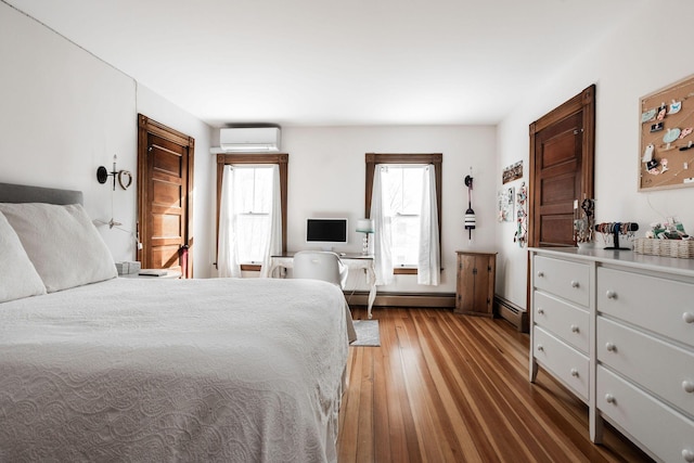 bedroom with hardwood / wood-style flooring, a baseboard heating unit, and a wall mounted air conditioner