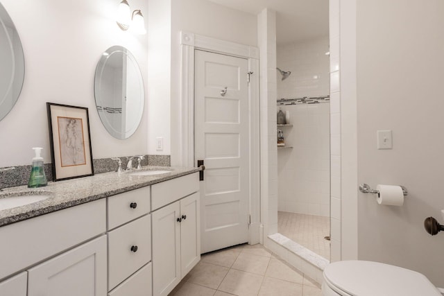 bathroom with a tile shower, vanity, tile patterned floors, and toilet