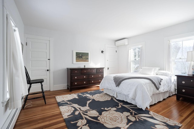 bedroom featuring multiple windows, wood-type flooring, an AC wall unit, and a baseboard radiator