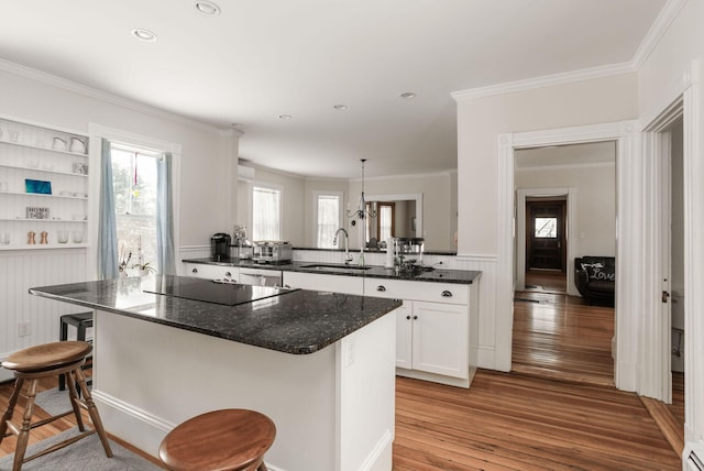 kitchen with pendant lighting, white cabinetry, sink, a kitchen breakfast bar, and black electric cooktop