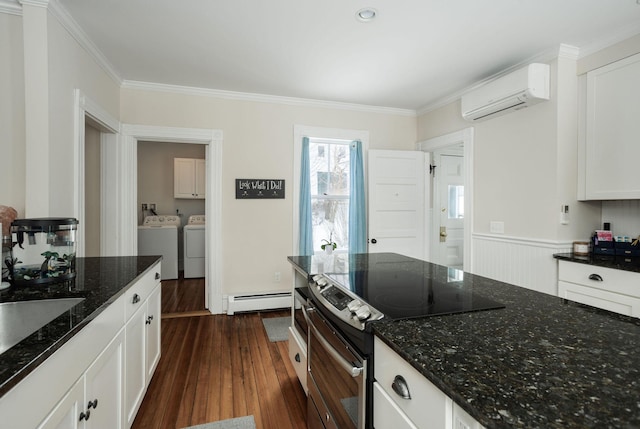 kitchen featuring white cabinets, dark stone counters, baseboard heating, washing machine and dryer, and electric stove