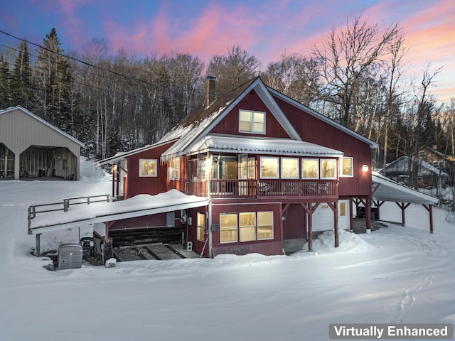 snow covered rear of property featuring a carport