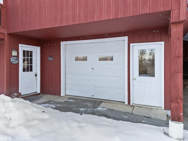 snow covered property entrance with a garage