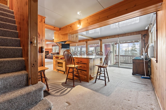 interior space featuring a breakfast bar, light colored carpet, wooden walls, and kitchen peninsula